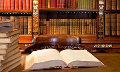 Open book in front of a wooden bookshelf filled with law books